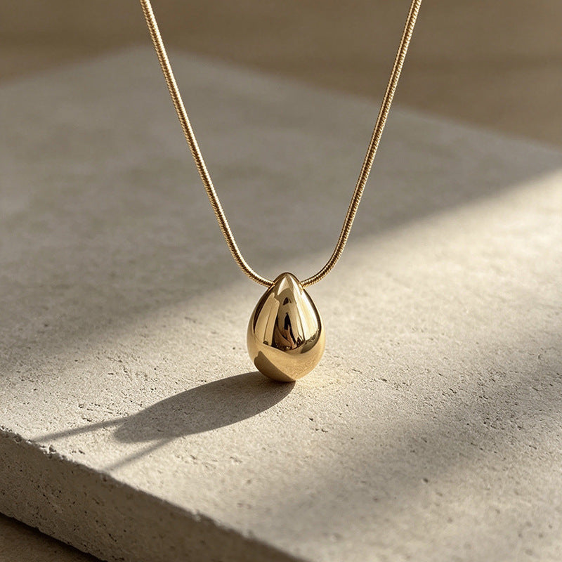 Aqua sculptural drop necklace on a light surface