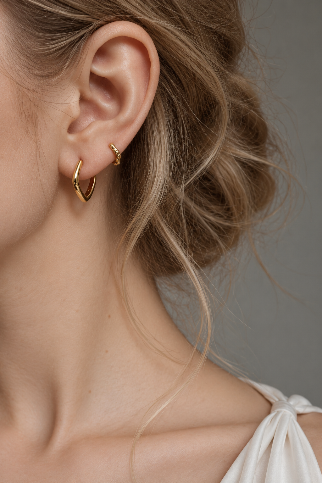 Model wearing a gold Noma organic huggie earring