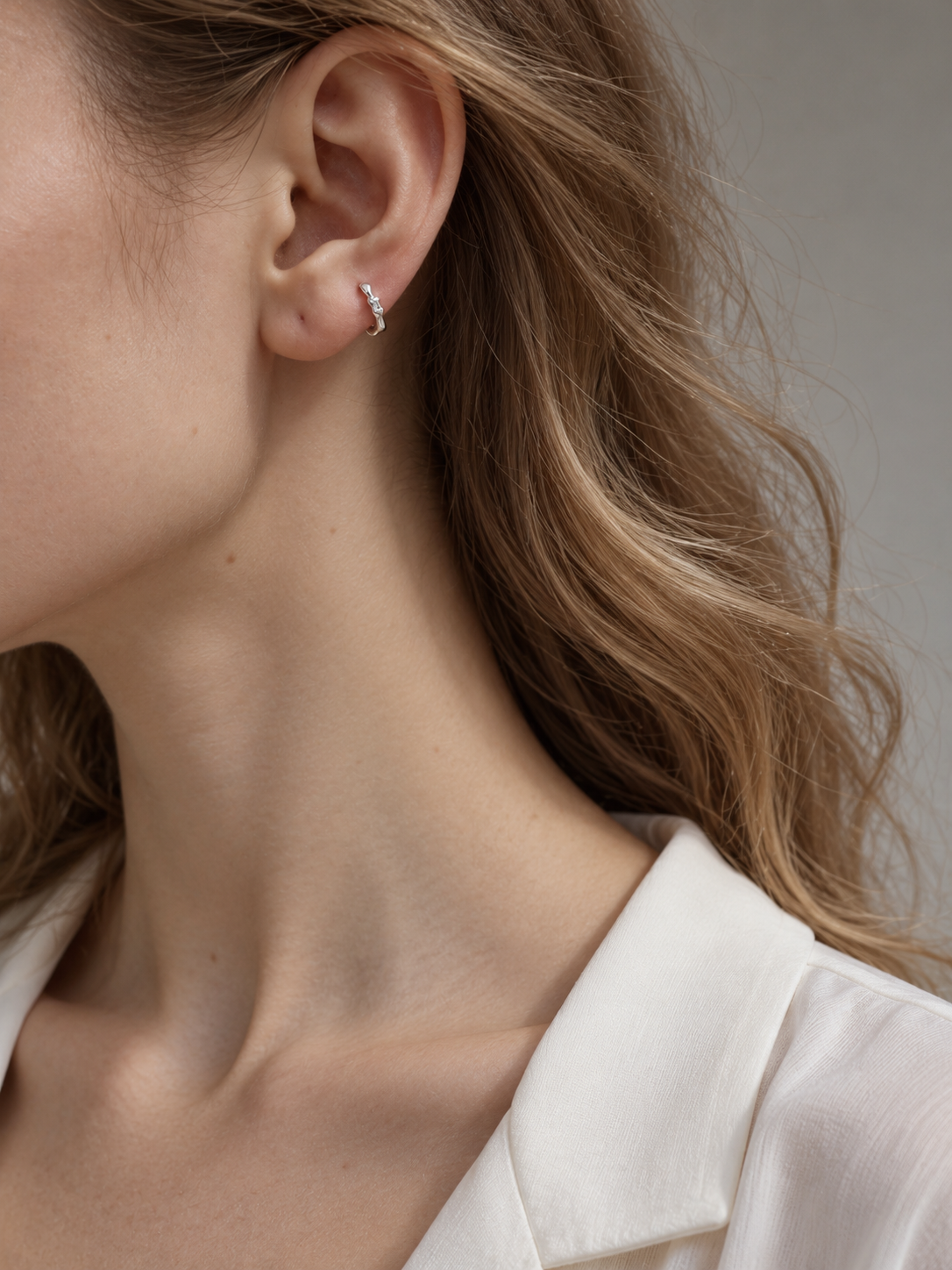 Model wearing a silver Noma organic huggie earring