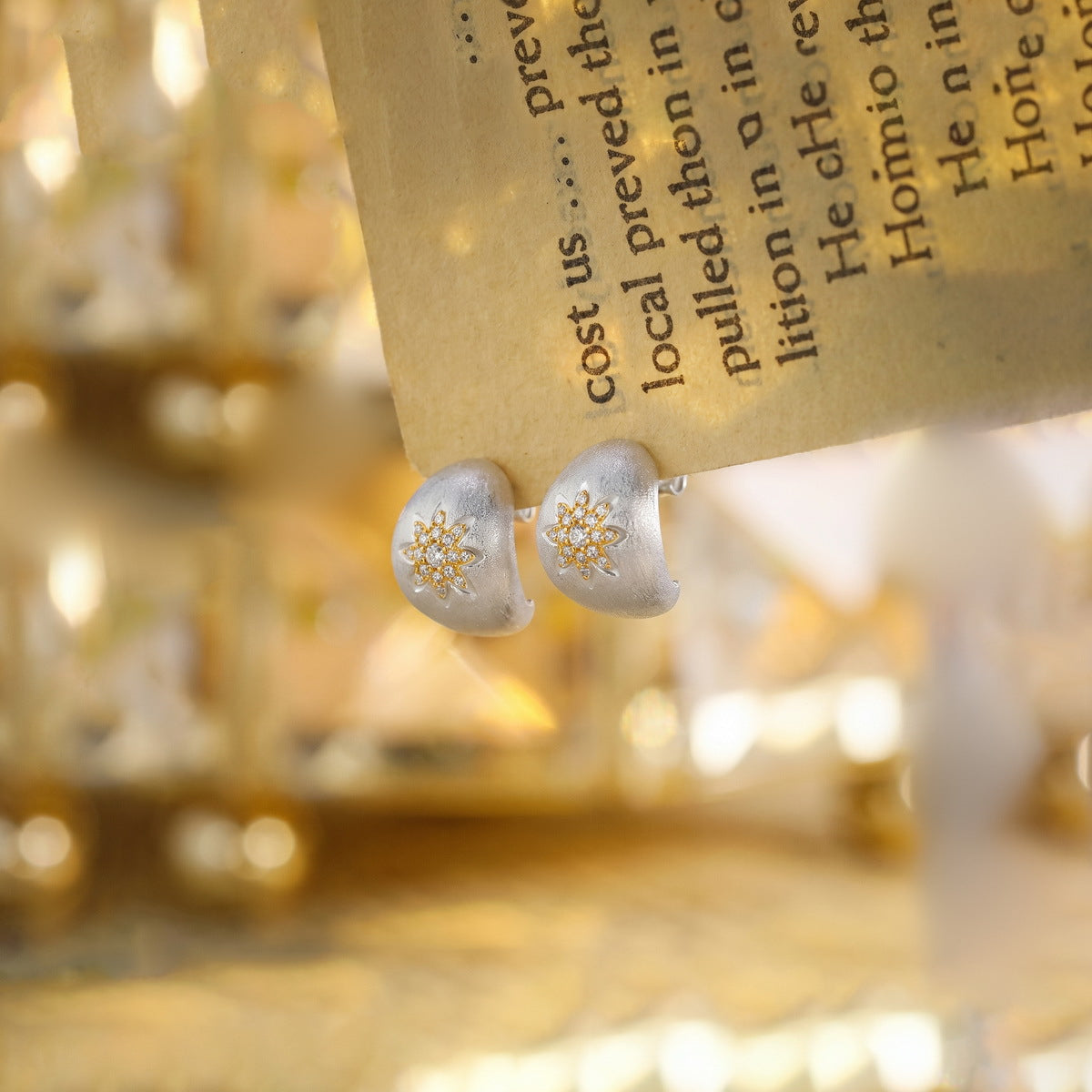 Astra two-tone zircon stud earrings on a warm surface