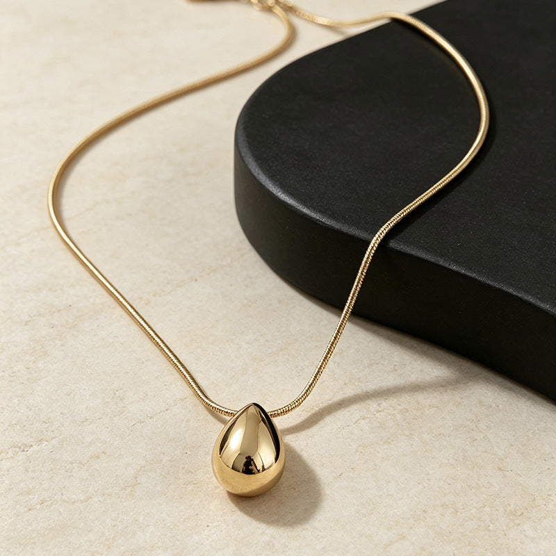 Aqua sculptural drop necklace draped on a dark form