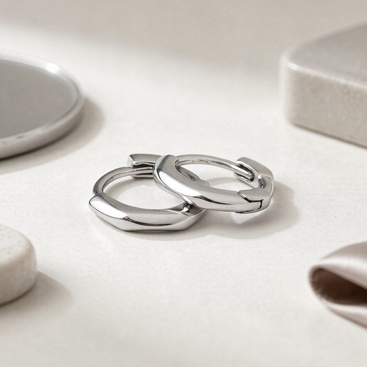 Silver Nia mini huggie hoop earrings on a white surface