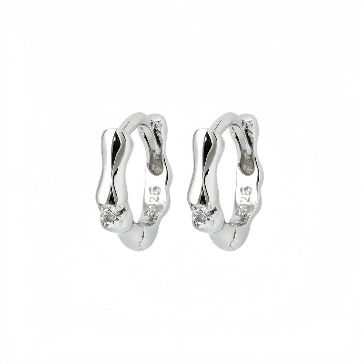 Silver Noma organic huggie earrings on a white background