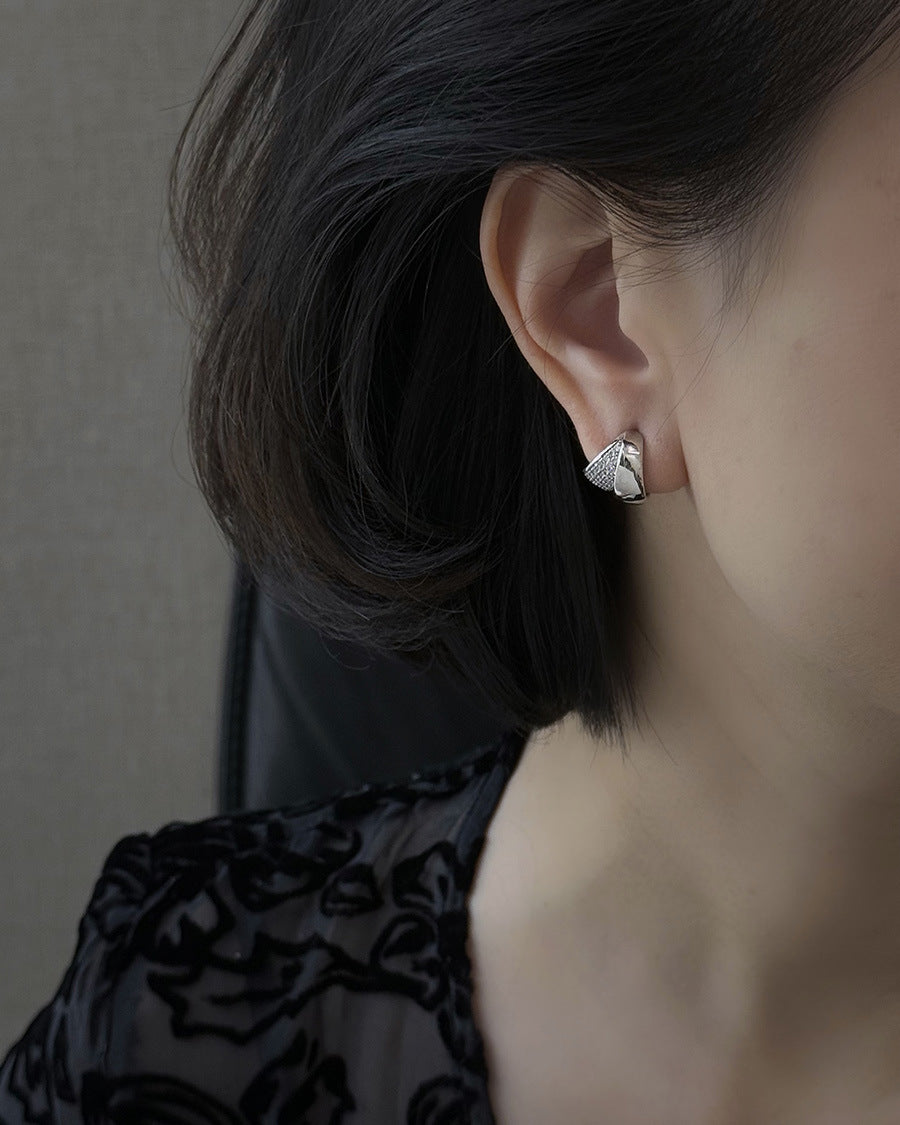 Close-up of Mira silver earrings with sculptural curves and pavé zircon